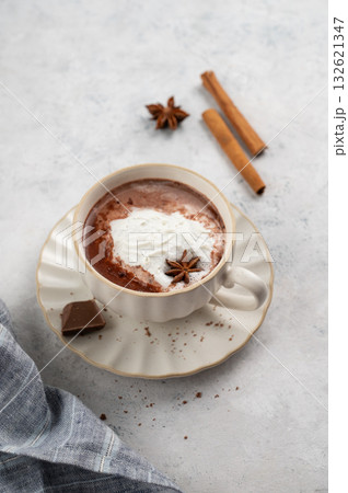 Hot chocolate in a cup with whipped cream and spices on a light background with napkin. 132621347