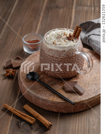 Hot chocolate in a cup with whipped cream and spices on a rustic dark wooden background. Hot chocolate in a cup with whipped cream and spices on a rustic dark wooden background. 132621359