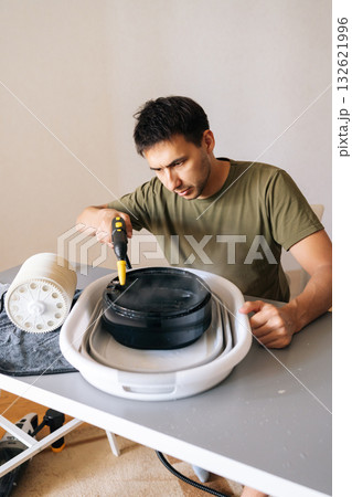 Vertical shot of focused man meticulously cleaning filter of air humidifier with steam cleaner, promoting optimal performance and maintaining high standards of hygiene for indoor air quality. Vertical shot of focused man meticulously cleaning filter of air humidifier with steam cleaner, promoting optimal performance and maintaining high standards of hygiene for indoor air quality. 132621996