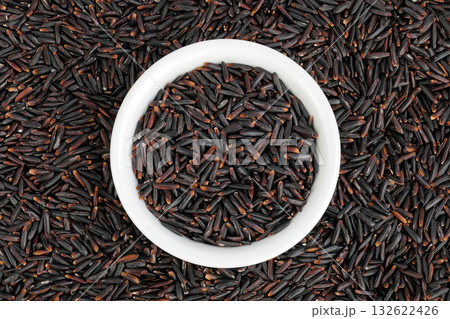 Black rice in a ceramic bowl as a background. Top view. Flat lay 132622426