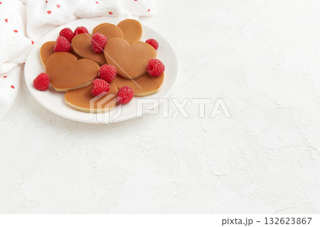 A heap of heart shaped pancakes with raspberries on the white plate on the white background 132623867