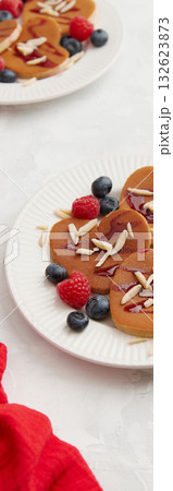Web banner of heap of heart shaped pancakes with berries on the white plate on grey background Web banner of heap of heart shaped pancakes with berries on the white plate on grey background 132623873