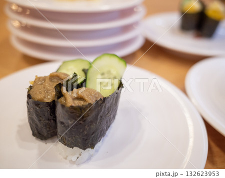 【日本】回転寿司屋のテーブル上に並ぶ軍艦巻きと食べ終わって積み上げられたたくさんの皿 132623953