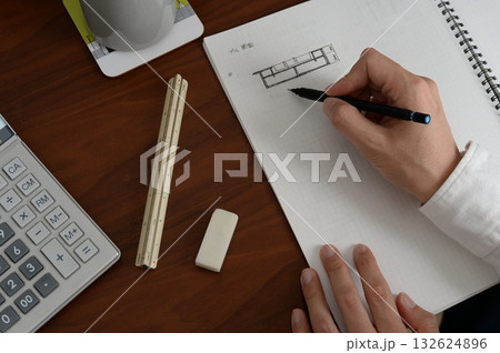 建築士が方眼ノートにプランを検討している手元の風景 132624896