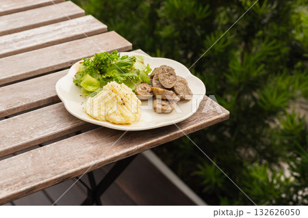 Grilled pork sausage with mash potato and vegetable salad in a white plate on table. Grilled pork sausage with mash potato and vegetable salad in a white plate on table. 132626050