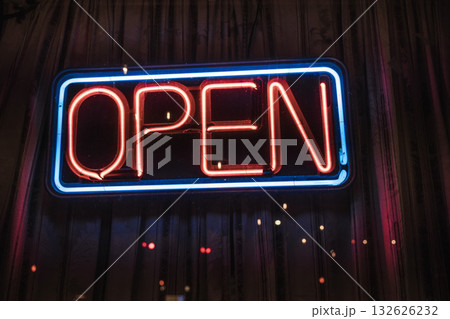 Bright neon open sign glowing in red and blue colors at night on a storefront window. Bright neon open sign glowing in red and blue colors at night on a storefront window. 132626232