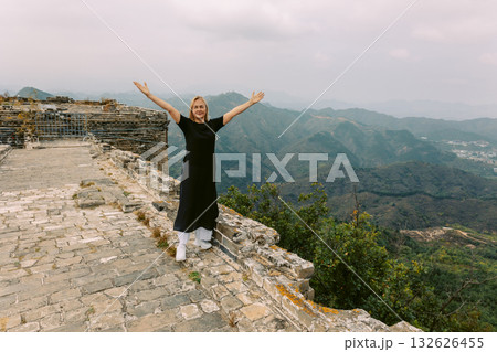 Happy woman on Simatai section of Great Wall of China in its original, un-restored state. Watchtowers perched on mountain peaks, China, Beijing. High quality photo Happy woman on Simatai section of Great Wall of China in its original, un-restored state. Watchtowers perched on mountain peaks, China, Beijing. High quality photo 132626455