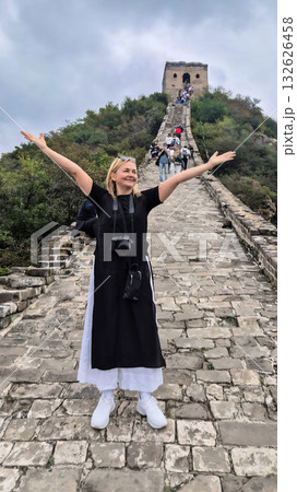 Happy woman on Simatai section of Great Wall of China in its original, un-restored state. Watchtowers perched on mountain peaks, China, Beijing. Vertical photo. High quality photo 132626458