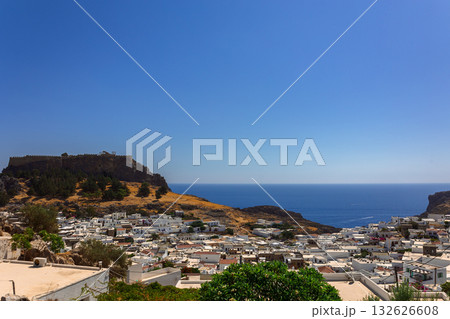 Panoramic view of colorful harbor in Lindos village and Acropolis, Rhodes. Aerial view of beautiful landscape, ancient ruins, sea with sailboats and coastline of island of Rhodes in Aegean Sea 132626608