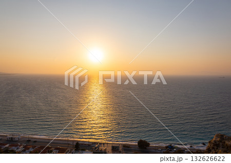 Panoramic view of Mediterranean Sea from sandy beach with rays of sun against backdrop of colorful sunset of Rhodes, Greece. Vacation, holiday concept. High quality photo 132626622
