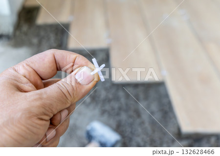 Tiler use plastic tile spacers for accurate alignment of floor tiles, Semi-dry floor screed. 132628466