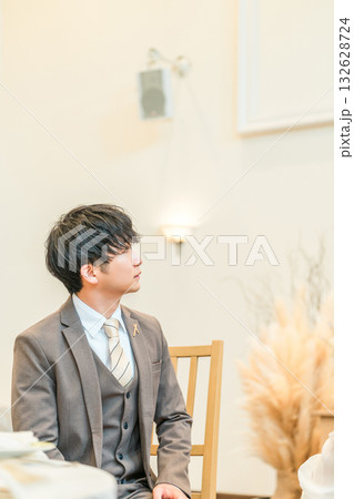 結婚式の披露宴の高砂席でスクリーンを見る新郎 132628724