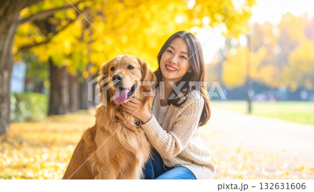 イチョウ並木の女性とゴールデンレトリバー 132631606