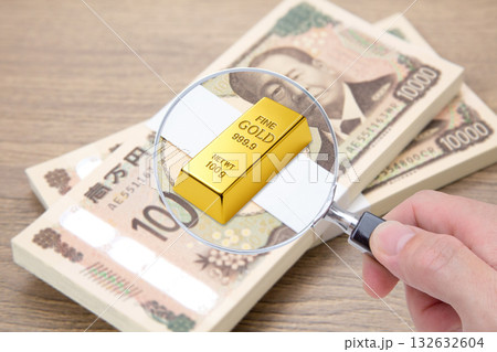 札束の上に置かれたゴールドのインゴットをクローズアップ 132632604