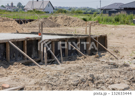 Workers are setting up a foundation slab for a new house in a developing neighborhood, with dirt and equipment nearby 132633444