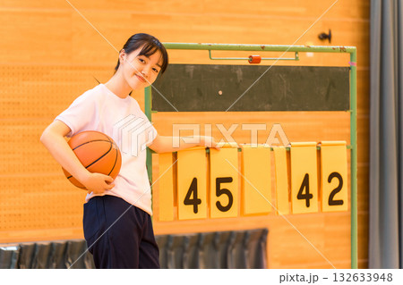 体育館でスコアボードをめくる体操着姿の女子生徒 132633948