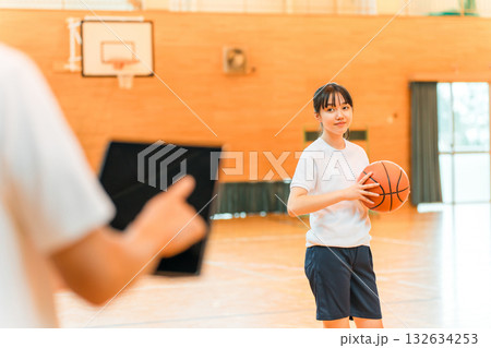 体育館でバスケットボールを持つ体操着姿の女子中学生・女子高生と男性教師 132634253