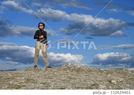 Middle-aged female tourist with a camera hiking in the mountains Middle-aged female tourist with a camera hiking in the mountains 132634401