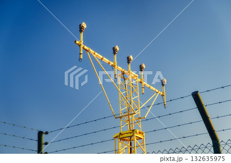 yellow metal structure with multiple arms and devices mounted at the top, an instrument landing system ILS located at an airport. The ILS is a radio navigation system  132635975