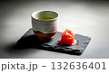 Still life composition, Wabi-sabi aesthetic. a simple hand-thrown ceramic cup filled with pale green soy sauce, next to a single piece of pickled ginger (gari) on a cracked slate Still life composition, Wabi-sabi aesthetic. a simple hand-thrown ceramic cup filled with pale green soy sauce, next to a single piece of pickled ginger (gari) on a cracked slate 132636401
