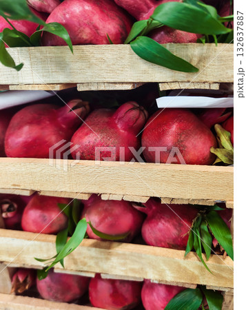 Fresh pomegranates stacked on wooden crates in a vibrant market setting 132637887