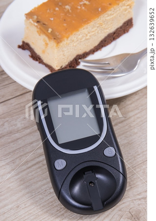 Glucose meter and piece of sweet cheesecake. Checking sugar level during diabetes 132639652