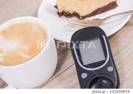 Glucose meter, piece of sweet cheesecake and cup of coffee with milk Glucose meter, piece of sweet cheesecake and cup of coffee with milk 132639654