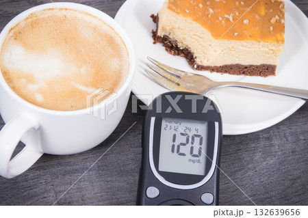 Glucose meter with high result sugar level, portion of sweet cheesecake and cup of coffee with milk Glucose meter with high result sugar level, portion of sweet cheesecake and cup of coffee with milk 132639656