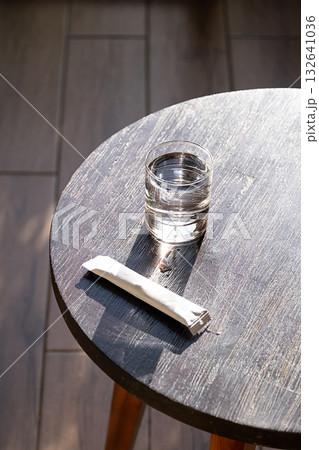 Glass of water and white sachet on wooden table. Refreshment and medication. Glass of water and white sachet on wooden table. Refreshment and medication. 132641036
