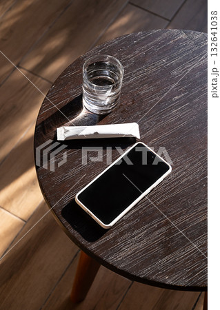 Water glass, health supplement stick pack and smartphone on wooden table. Water glass, health supplement stick pack and smartphone on wooden table. 132641038