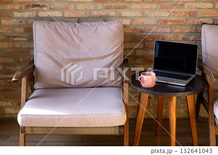 Cozy outdoor lounge chair with laptop and coffee cup on side table. 132641043