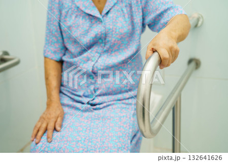 Asian elderly woman patient use toilet support rail in bathroom. 132641626
