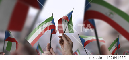 Equatorial Guinea flags in their hands on a blurred urban background Equatorial Guinea flags in their hands on a blurred urban background 132641655