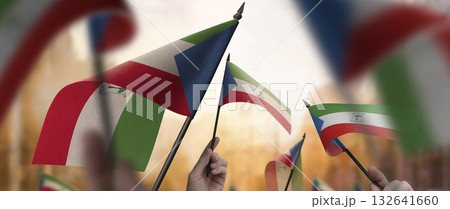 Equatorial Guinea flags in their hands on a blurred urban background 132641660