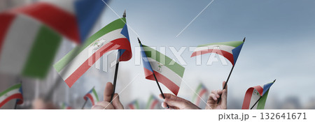 Equatorial Guinea flags in their hands on a blurred urban background 132641671