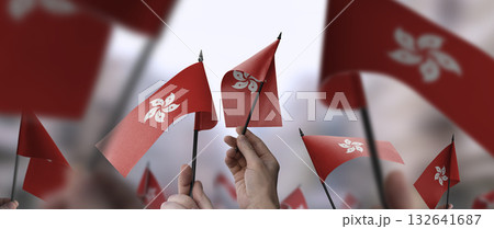 Hong Kong flags in their hands on a blurred urban background Hong Kong flags in their hands on a blurred urban background 132641687