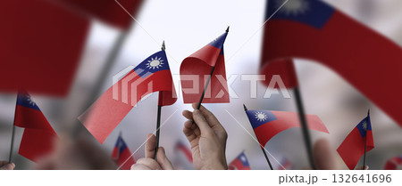 Taiwan flags in their hands on a blurred urban background Taiwan flags in their hands on a blurred urban background 132641696