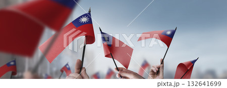Taiwan flags in their hands on a blurred urban background Taiwan flags in their hands on a blurred urban background 132641699