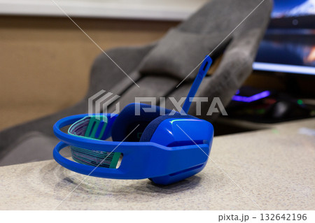 Blue gaming headphones on table with gaming computer in background. Concept photography for video gaming at home in a cozy, comfortable setting 132642196
