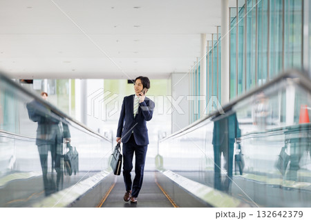 エスカレーターに乗るビジネスマン 132642379