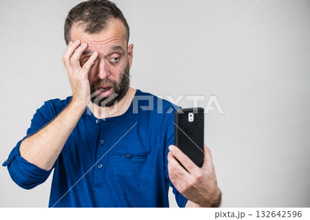 Worried adult man looking at smartphone 132642596