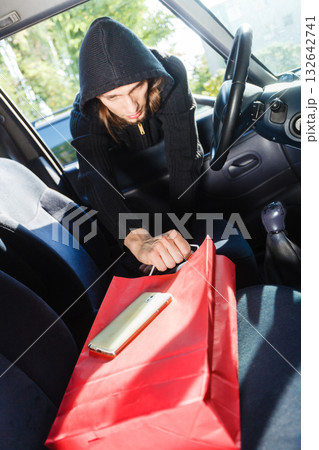 Burglar thief stealing smartphone and bag from car 132642741