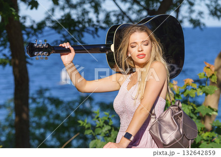 Woman playing acoustic guitar in park Woman playing acoustic guitar in park 132642859