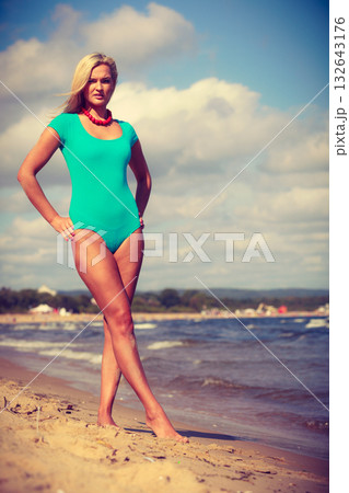 Woman walking on beach wearing swimsuit 132643176