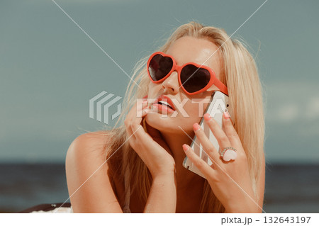 Girl on beach with phone. 132643197