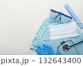 Healthcare background of disposable face mask, gloves, cap, goggles, scrubs and stethoscope laying on table flat lay view 132643400