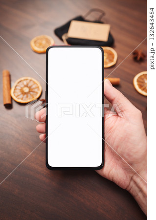 Man hand hold smarthone with white screen with christmas decorations on background 132643484