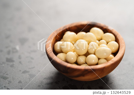 White chocolate or yogurt dragee with berries in olive wood bowl on concrete background White chocolate or yogurt dragee with berries in olive wood bowl on concrete background 132643529