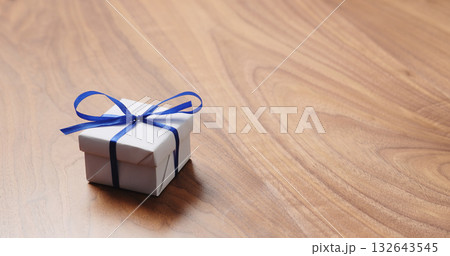 white paper gift box with blue ribbon on walnut table with copy space 132643545