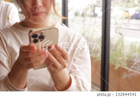 カフェでスマートフォンを操作する女性 カフェでスマートフォンを操作する女性 132644541